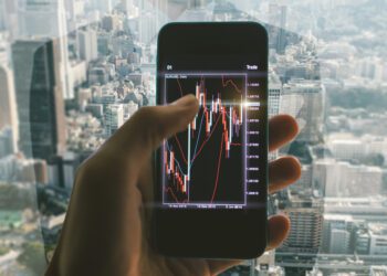 Business man making trading from his office. Close up on the smart phone with trading chart.